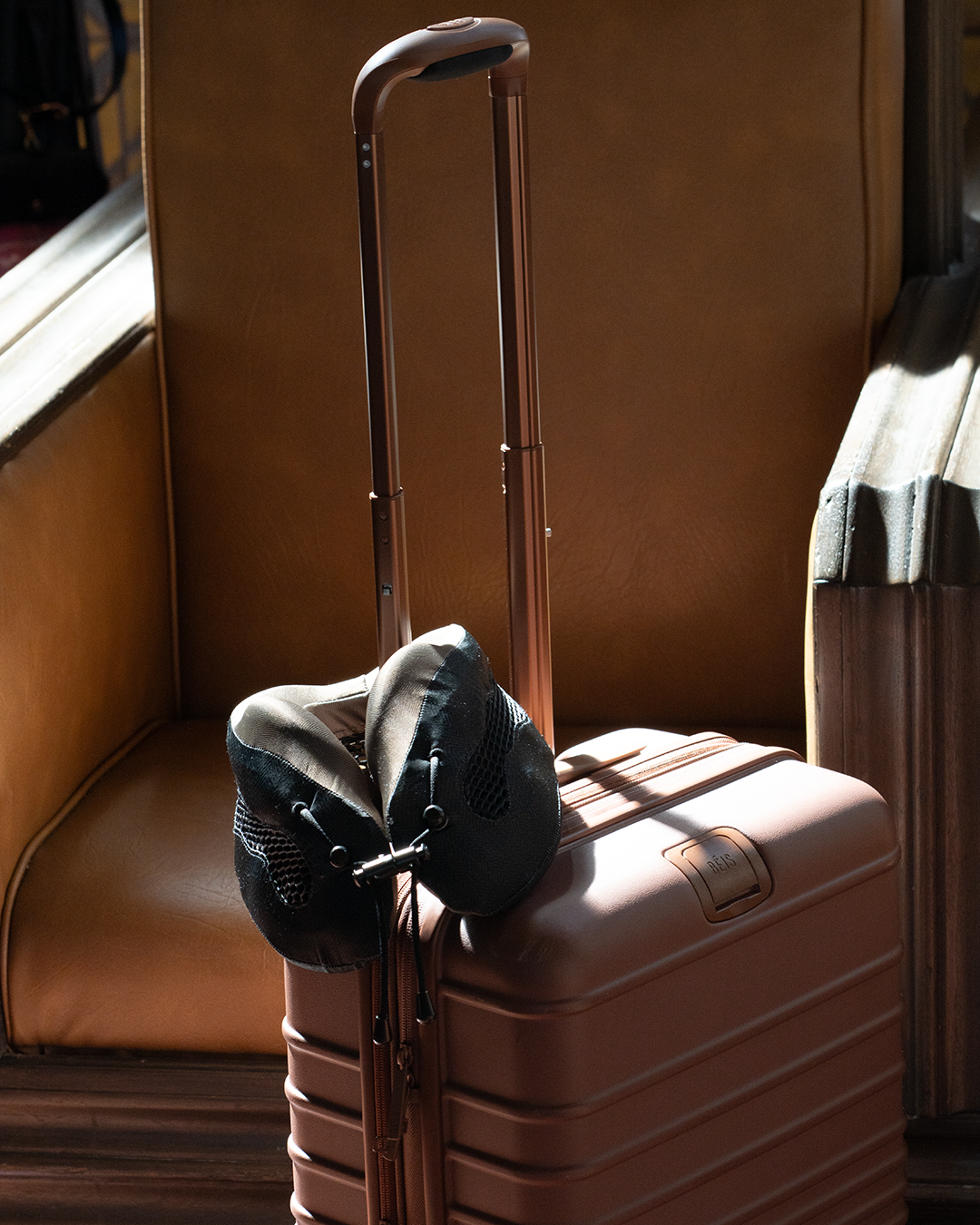 Brown suitcase with an Evolution Cool neck pillow sitting on top
